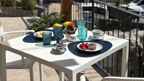 Una mesa servida con platos, tazas y vasos en un balcón con vistas panorámicas.