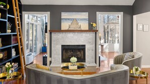 A living room with a fireplace, a bookshelf, and a view of the outdoors. - Pool, Tree House, Kids Game Room, Grilling & 20 Minutes to Atl Attractions (Lilburn)