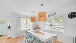 A dining area with a white table, light blue chairs, and a decorative centerpiece. - Manatee Cottage - Private Pool, Tropical Oasis! (Bradenton)