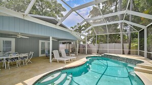 A covered outdoor swimming pool with a patio area, including a table and chairs, and a ceiling fan. - Manatee Cottage - Private Pool, Tropical Oasis! (Bradenton)