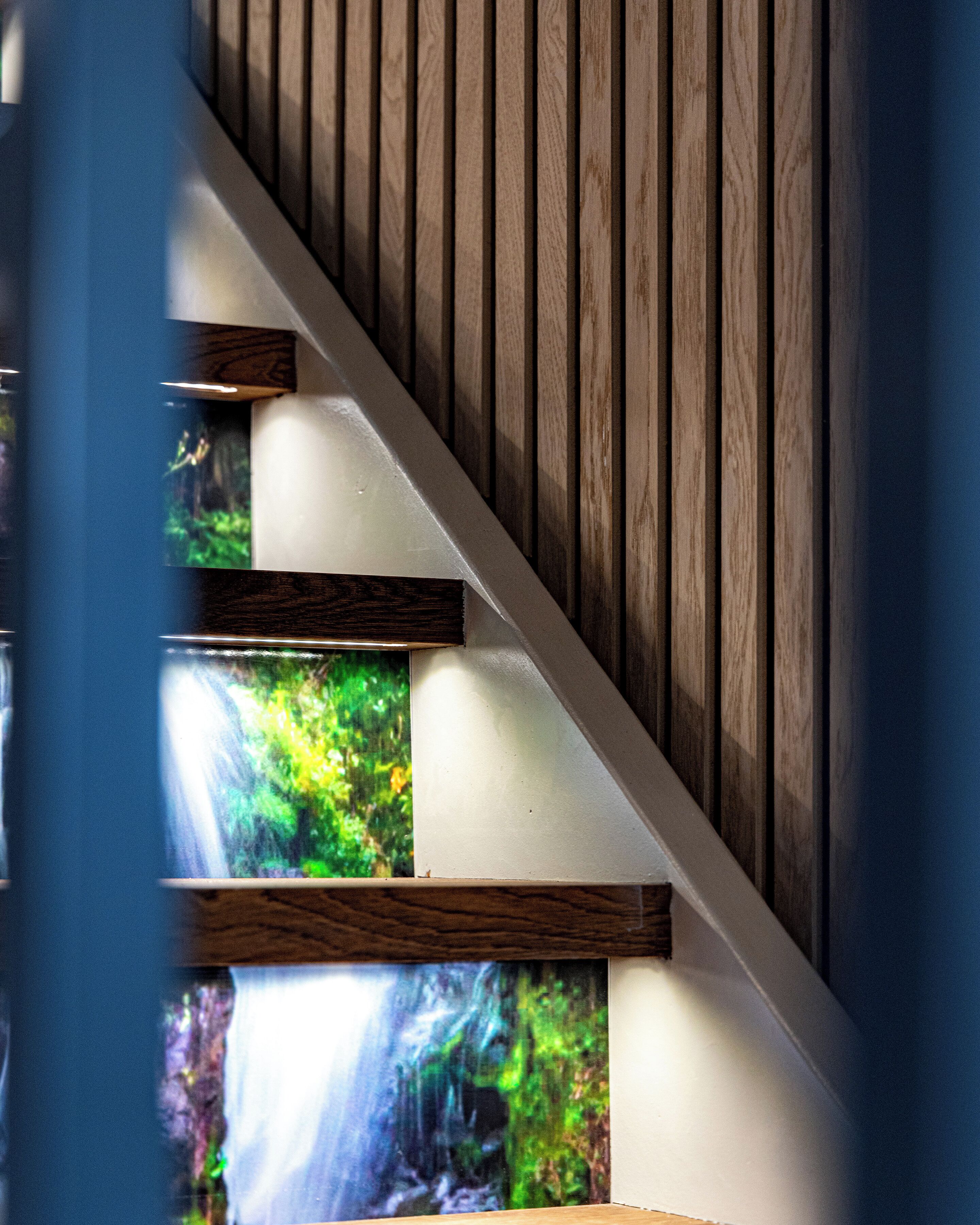 Eine Treppe mit Holzbodenstufen und einer Glasscheibe, die eine Wasserfallansicht zeigt.