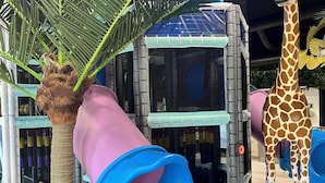 A play structure with a slide, a giraffe statue, and a palm tree. - Fun Art Blokhus (Blokhus)