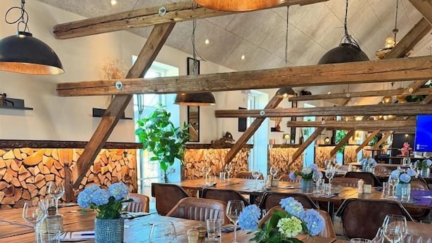 A restaurant with wooden tables, chairs, and hanging pendant lights. - Fun Art Blokhus (Blokhus)