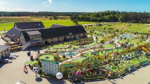 A golf course with a building, a Fun Art Farm, and a pool. - Fun Art Blokhus (Blokhus)