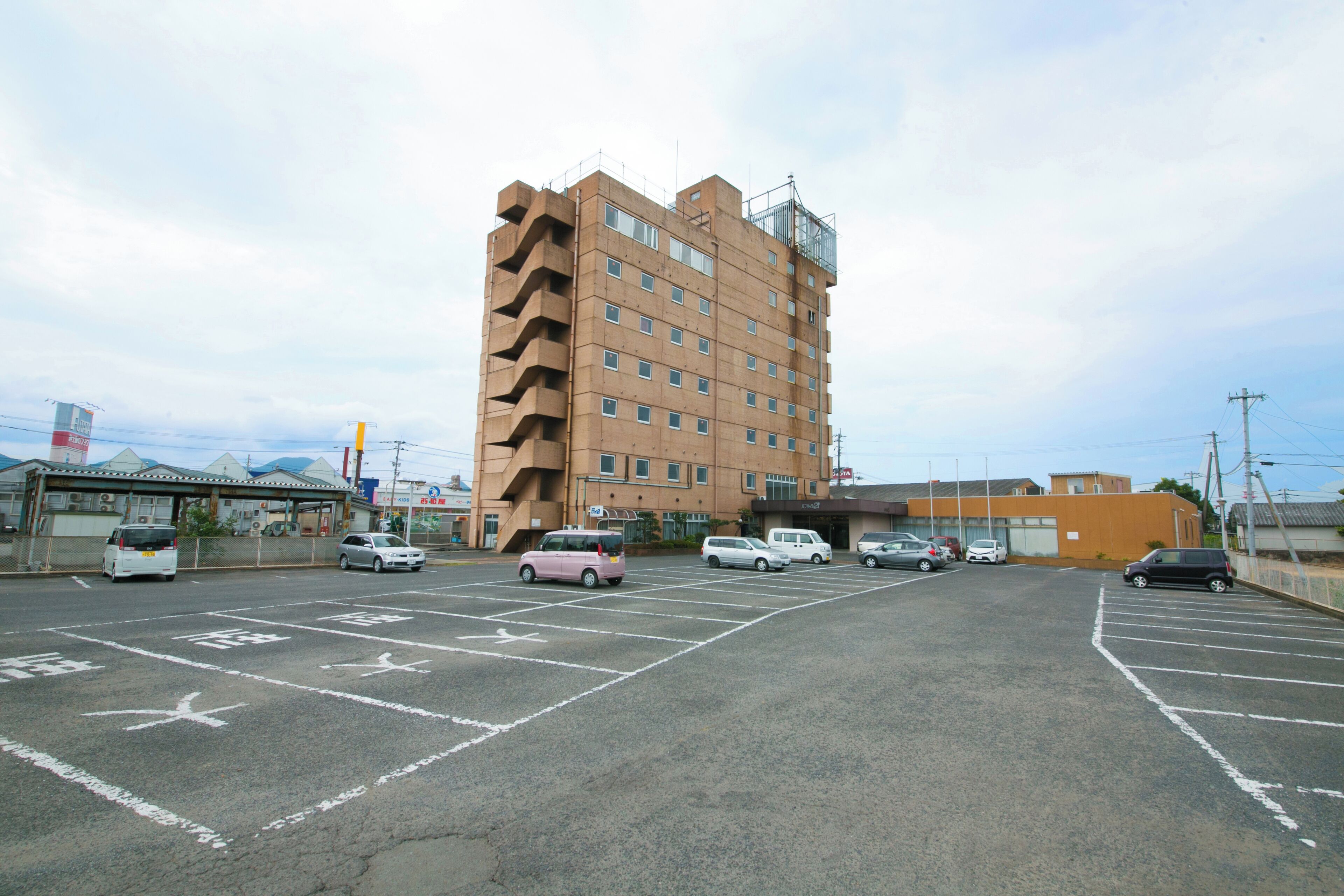 A parking lot with several cars and a multi-story building in the background.