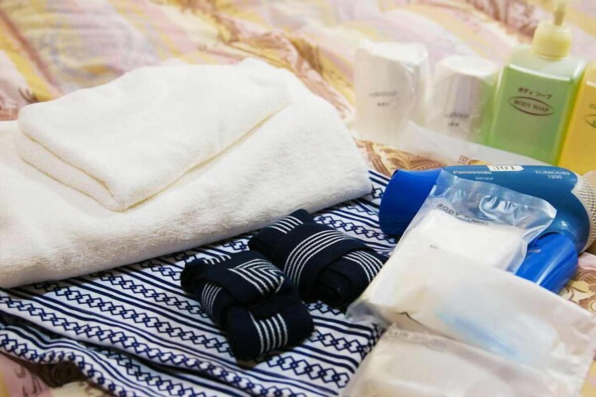A neatly arranged bathroom with a towel, toiletries, and a hairdryer.