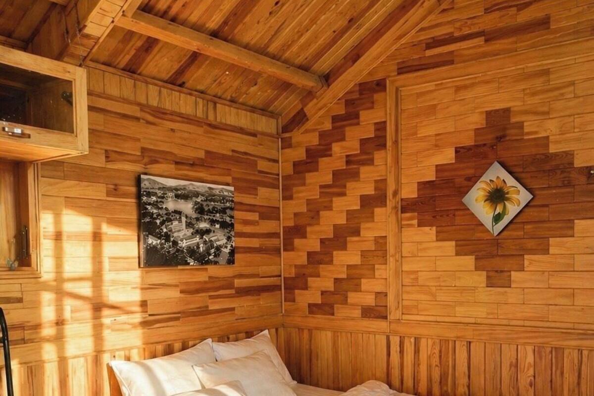 A wooden-paneled room with a bed, a picture on the wall, and a sunflower decoration.