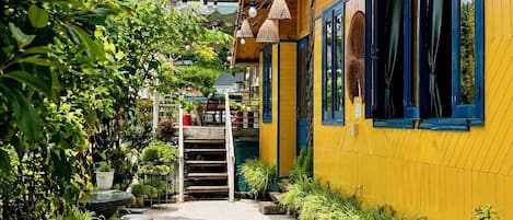 A yellow building with blue windows, a staircase, and potted plants.