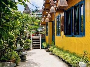 A yellow building with blue windows, a staircase, and potted plants. - Tomorrow Homestay Da Lat (Da Lat)