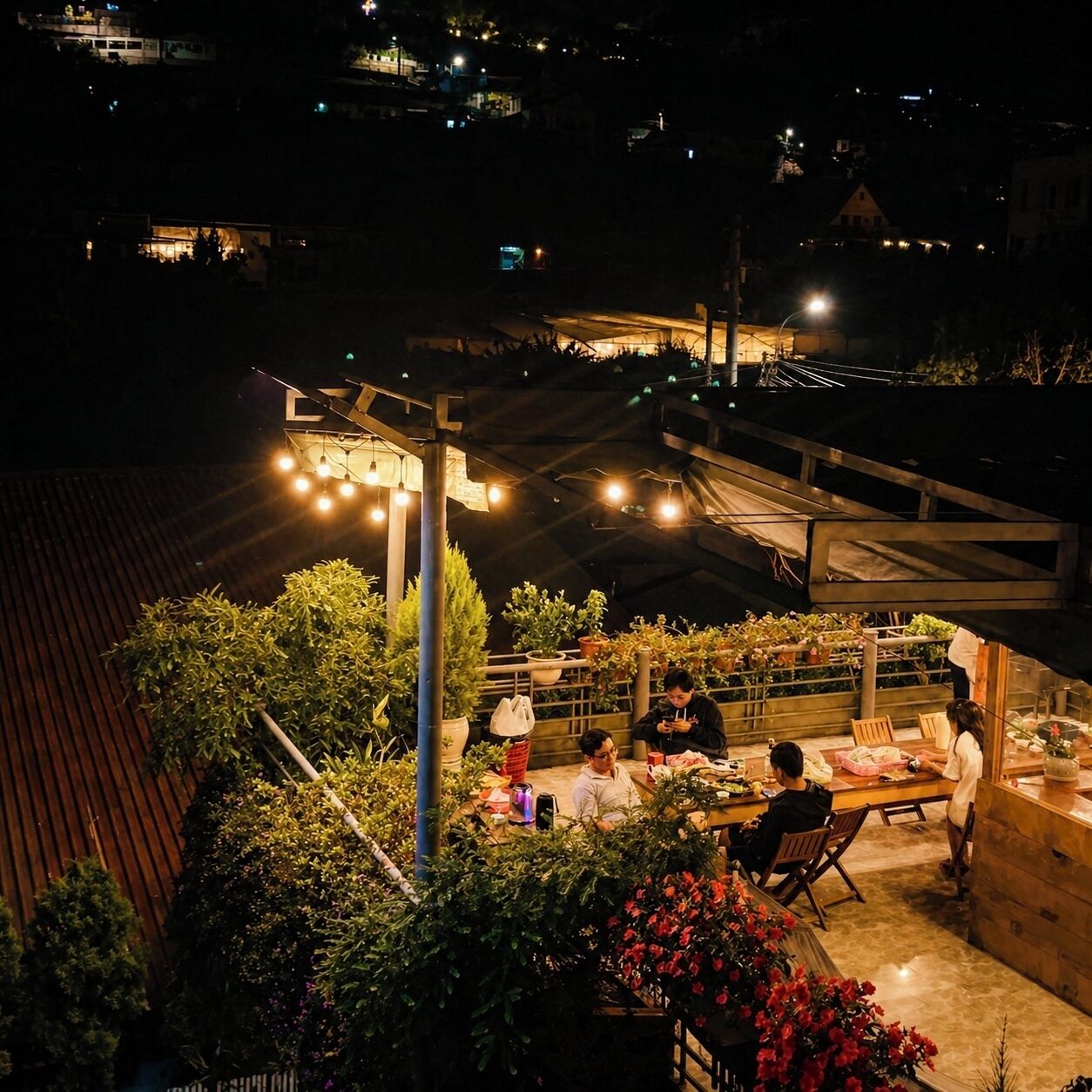 An outdoor dining area with tables and chairs, surrounded by potted plants and flowers.