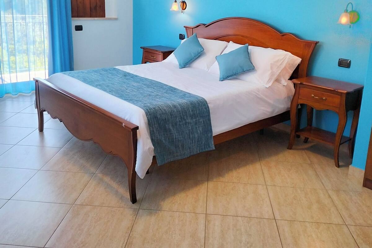 A bedroom with a wooden bed, blue walls, and two bedside tables with lamps.