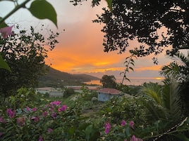 A landscape with a sunset, hills, and a body of water.