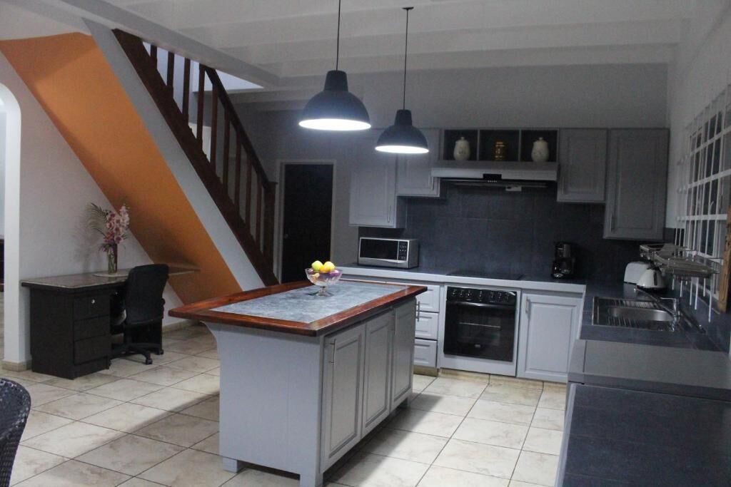 Una cocina moderna con una isla central, electrodomésticos integrados e iluminación colgante.