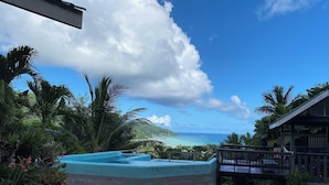 A tropical resort with a pool, a wooden deck, and a view of the ocean.