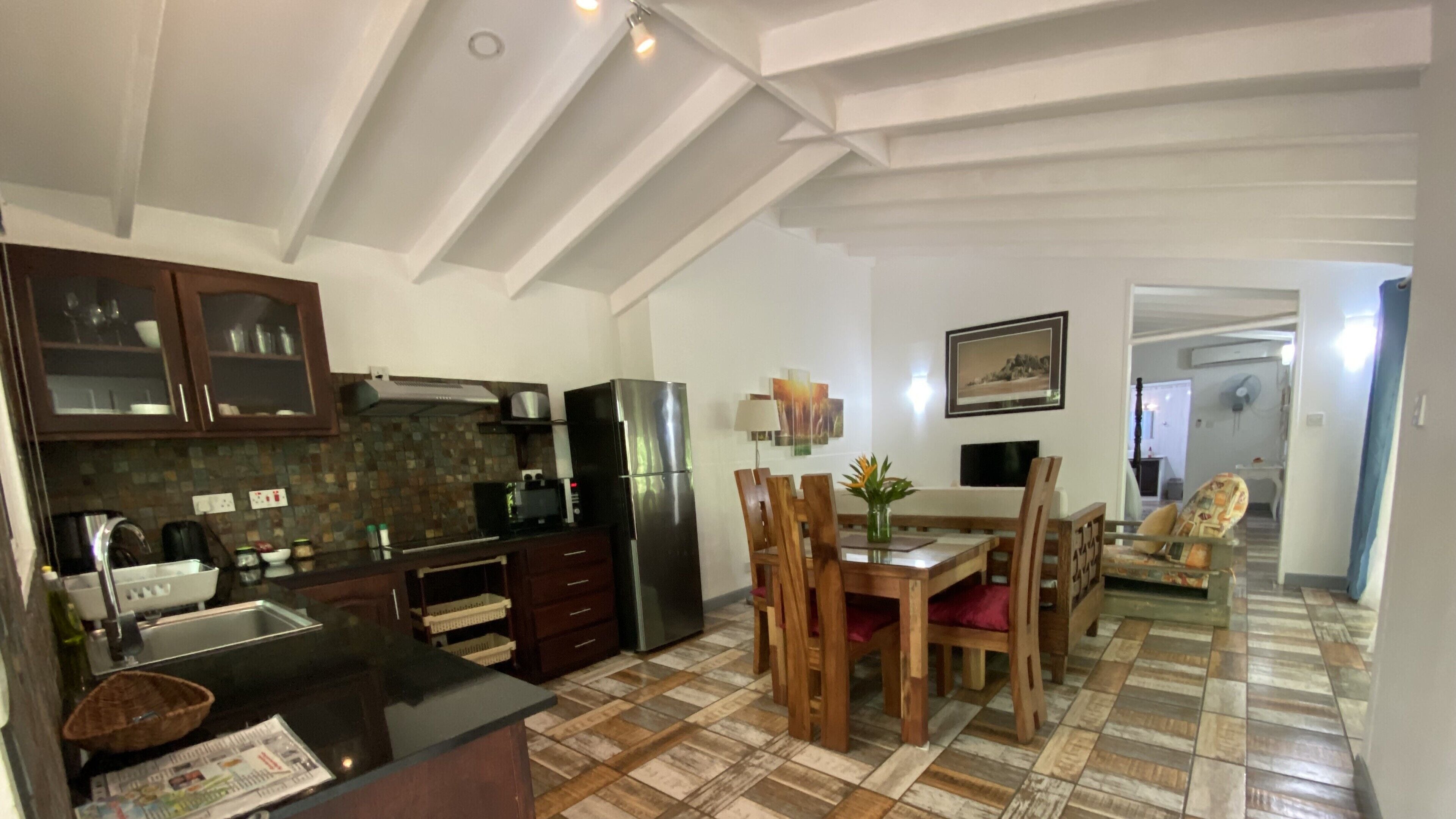 A kitchen with wooden cabinets, a refrigerator, and a dining area with a table and chairs.