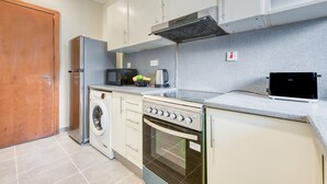 A compact kitchen with a washing machine, microwave, stove, and a small countertop area. - Luxury Stay at Madison 2bedroom Balcony (Dubai)