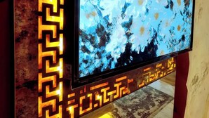 A flat-screen TV mounted on a wall with a decorative frame featuring a geometric pattern. - Leon Hotel (Absheron)