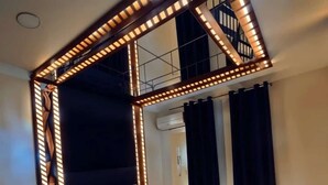 A modern bedroom with a bed, bedside tables, a patterned rug, and a ceiling light fixture. - Leon Hotel (Absheron)