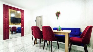 A dining area with a marble floor, red upholstered chairs, a wooden table, and a blue sofa. - Leon Hotel (Absheron)
