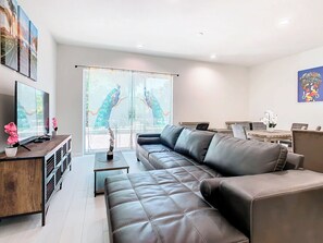 A modern living room with a leather sofa, a wooden coffee table, and a TV on a wooden stand.