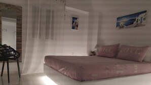 A bedroom with a bed, a chair, a mirror, and a painting on the wall.