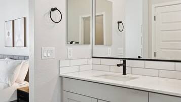 A modern bathroom with a white vanity, a large mirror, and a door.