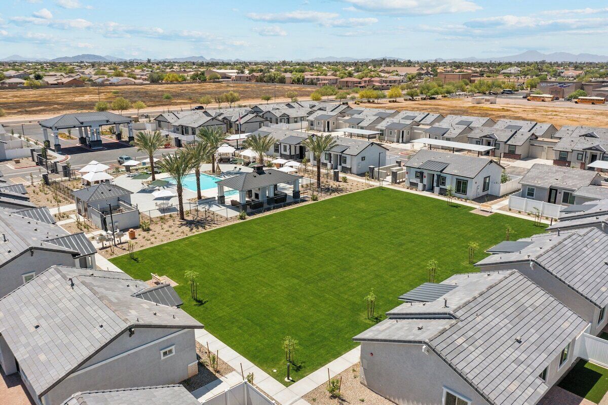 A residential area with modern houses, a central green lawn, and a swimming pool.