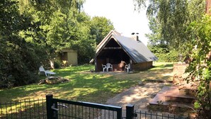 Un chalet rustique doté d’un toit en pente, entouré d’une pelouse bien entretenue et d’arbres.