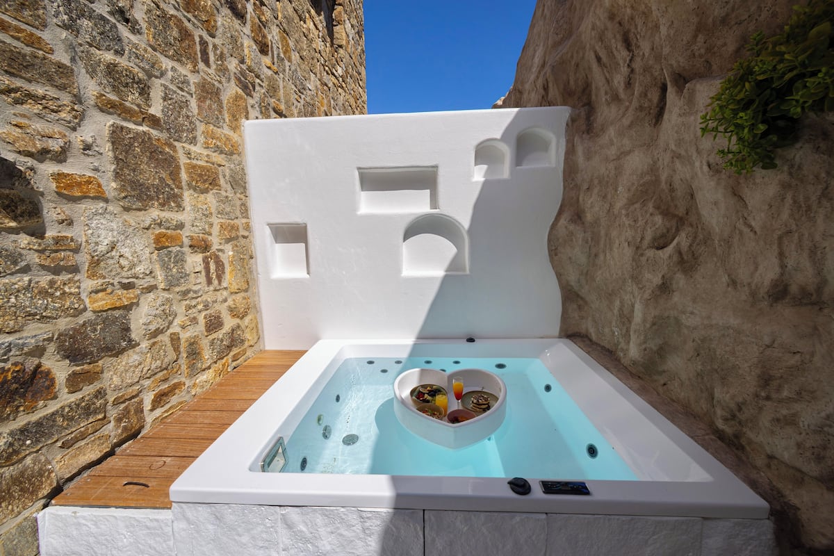 Un bain à remous avec un bassin en forme de cœur, installé devant un mur de pierre.