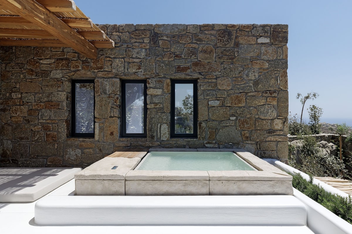 Un bâtiment en pierre doté d’une piscine et d’une pergola en bois.