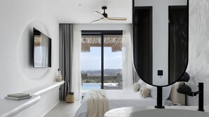 A modern bedroom with a large bed, a round bathtub, and a view of a pool. - WhiteArt Suites (Mykonos)