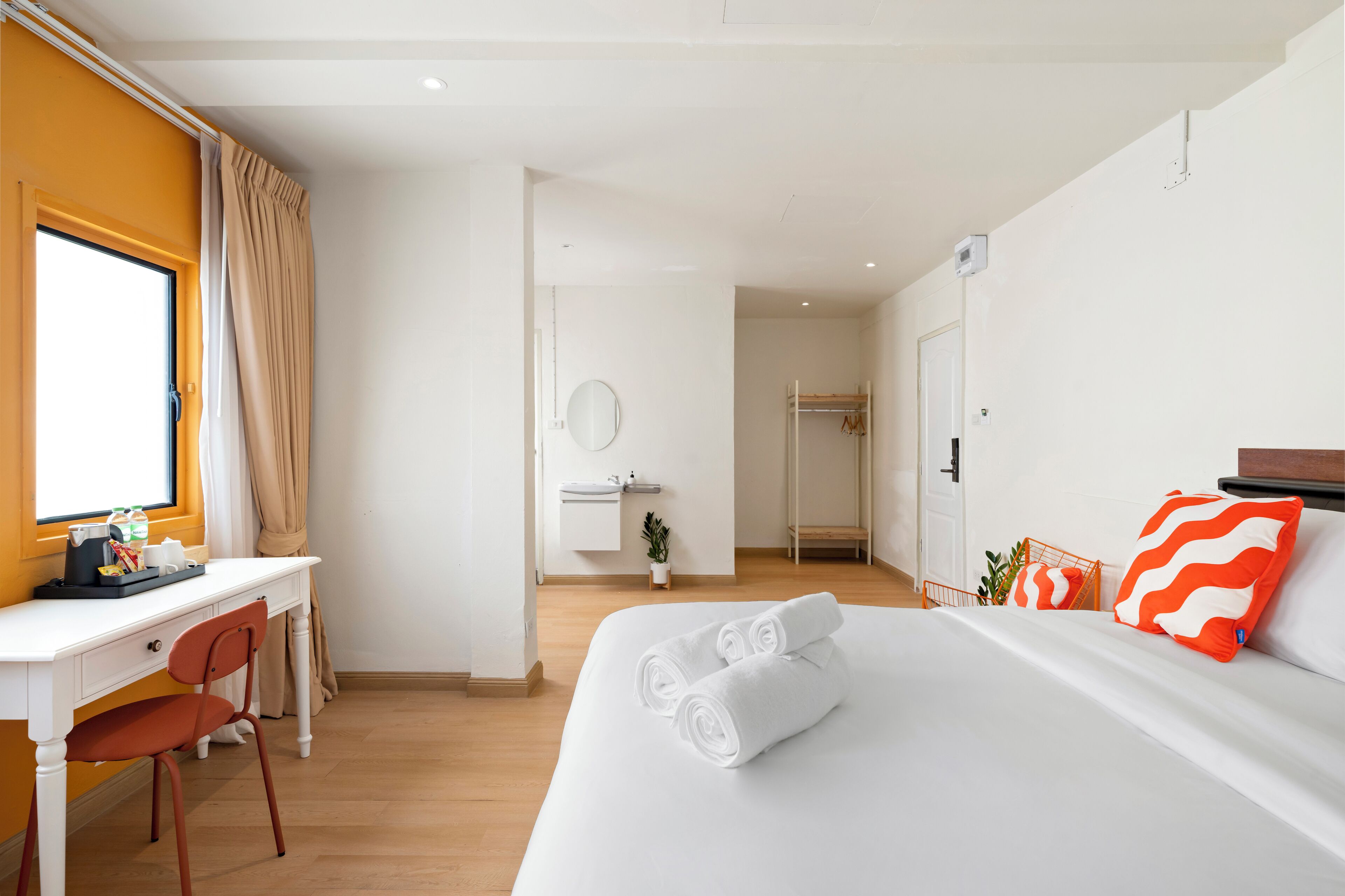 Habitación de hotel con cama, escritorio, silla, baño y vistas al exterior.