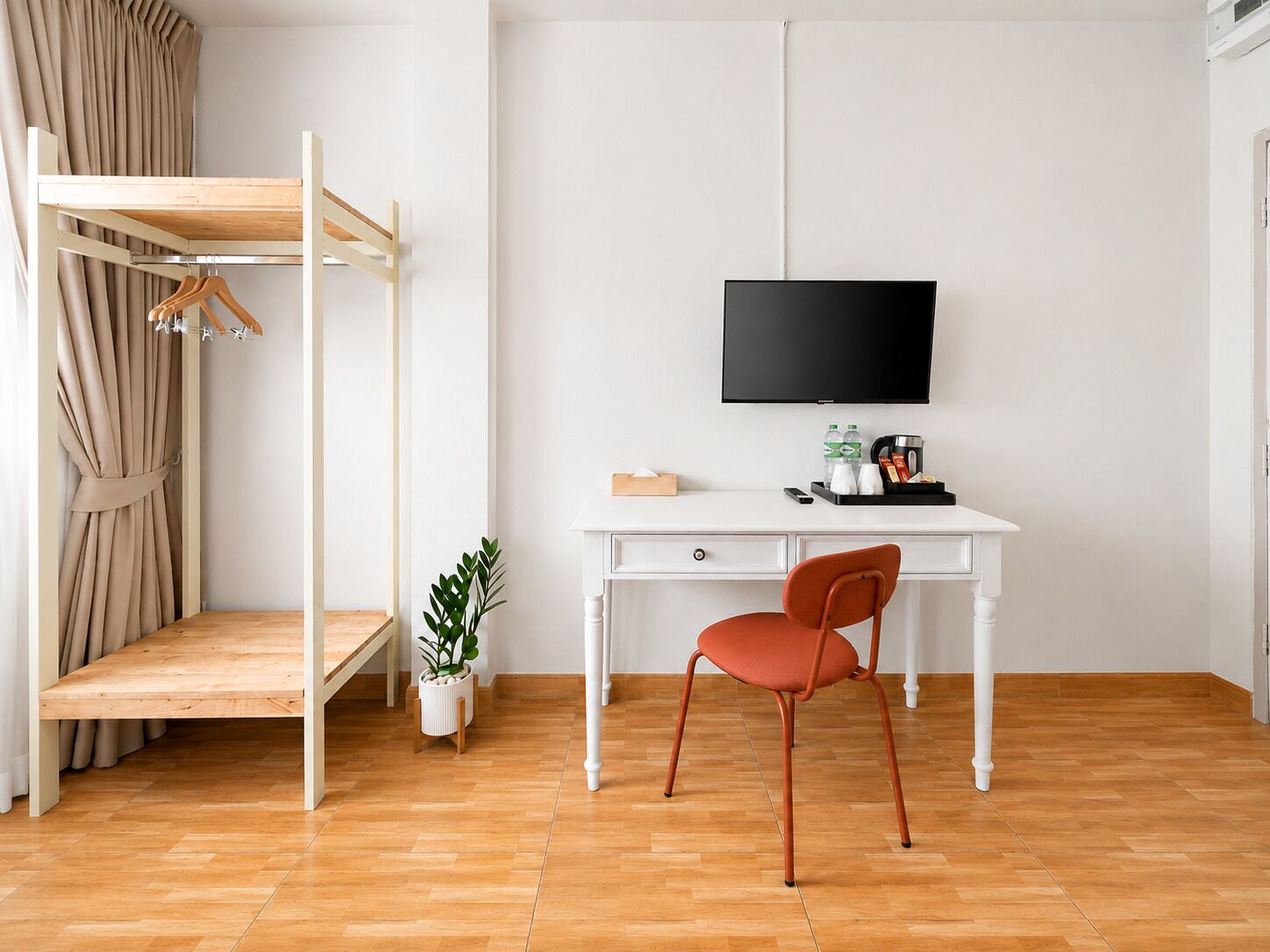 A room with a bunk bed, a desk with a chair, a television, and a small plant.
