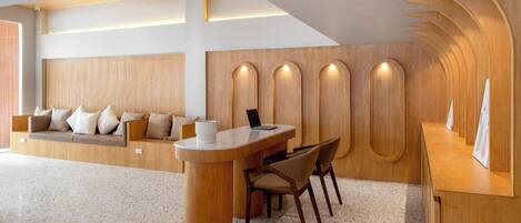 A modern reception area with a wooden reception desk, seating area, and a wall with built-in niches.