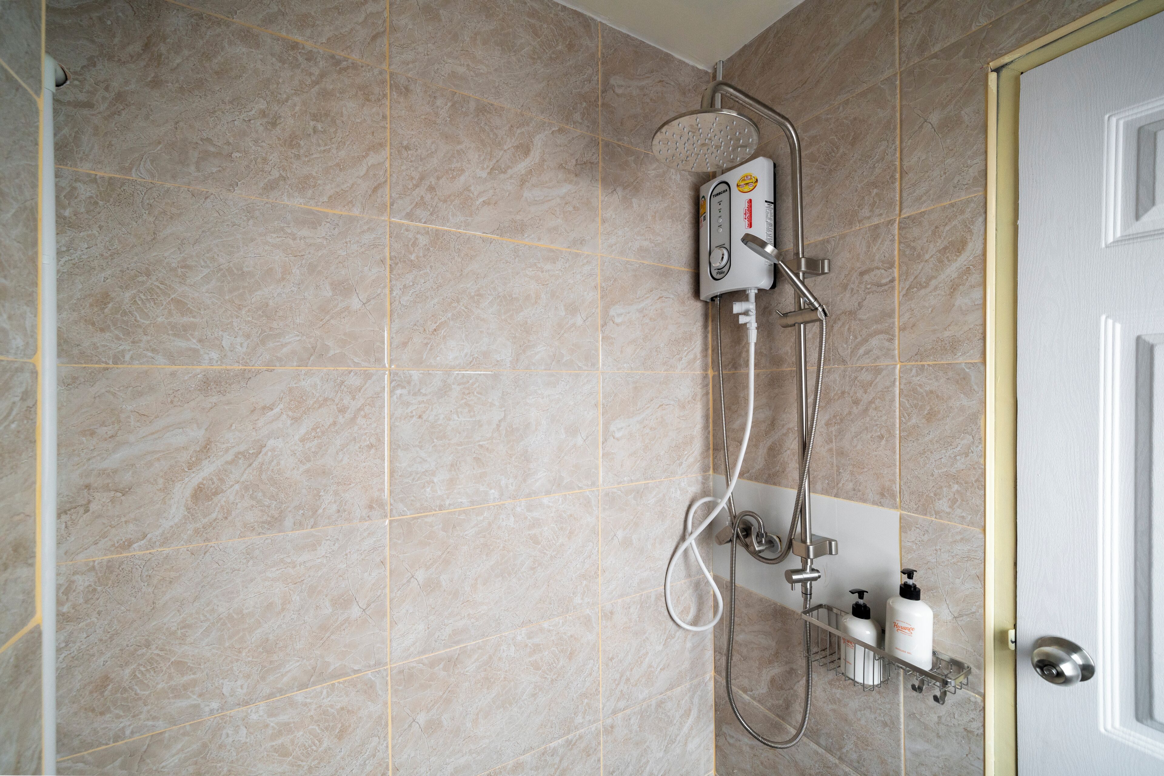 Un baño con cabina de ducha, secamanos y dispensador de jabón en un estante.