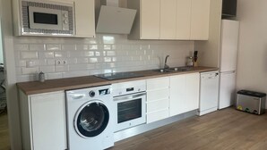 Una cocina compacta con lavadora y secadora integradas, microondas y un lavamanos.