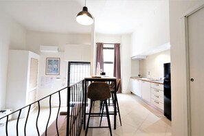 A modern kitchen with a dining area, featuring a kitchen island, a refrigerator, and a hanging light fixture. - Wine Apartments Florence Amarone (Firenze)