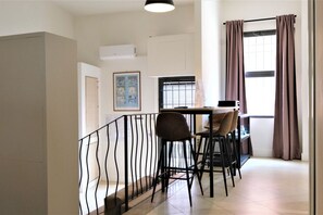 A dining area with a table, chairs, and a view of the outside through a window with curtains. - Wine Apartments Florence Amarone (Firenze)