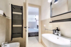 A modern bathroom with a bathtub, a sink, and a towel rack. - Wine Apartments Florence Amarone (Firenze)