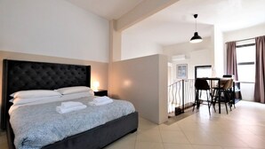 A modern hotel room with a large bed, a dining area, and a view of the city. - Wine Apartments Florence Amarone (Firenze)