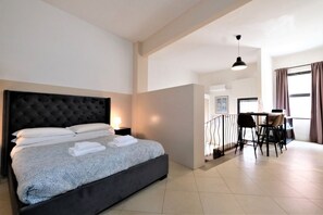 A modern hotel room with a large bed, a dining area, and a view of the city. - Wine Apartments Florence Amarone (Firenze)