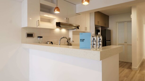 A modern kitchen with a central island, stainless steel appliances, and pendant lighting. - w* | Sophisticated 2BR with Balcony in Miraflores (Lima)