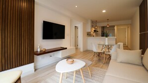 A modern living room with a flat-screen TV, a dining area with a table and chairs, and a sofa. - w* | Sophisticated 2BR with Balcony in Miraflores (Lima)