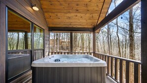 Un bain à remous sur une terrasse en bois, avec vue sur les arbres.