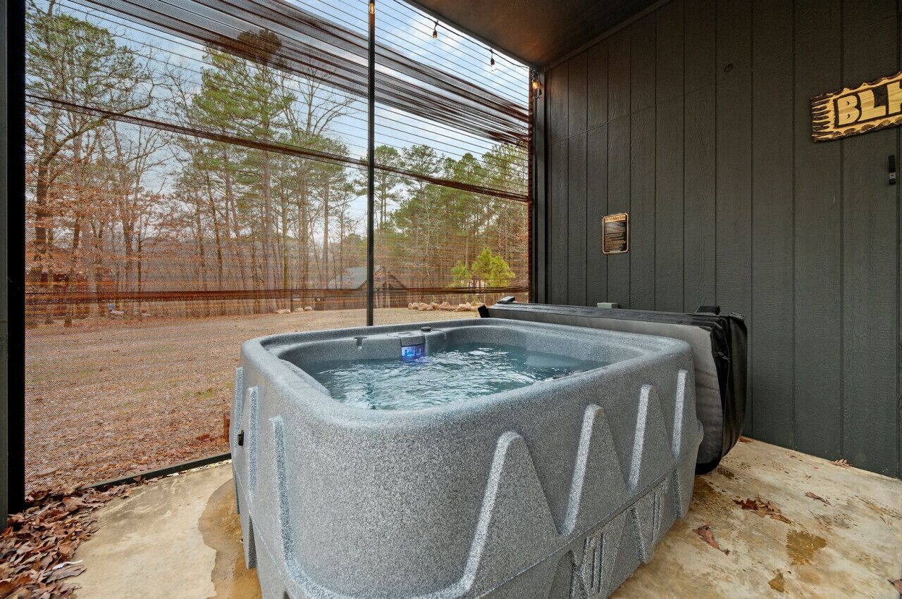 Ein Whirlpool in einem Zimmer mit großem Fenster mit Blick auf ein bewaldetes Gebiet.