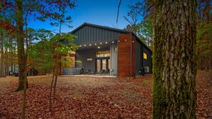 Een modern gebouw met een overdekt terras, omringd door bomen en herfstbladeren.