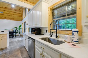 A modern kitchen with white cabinetry, a large window, and a sink.