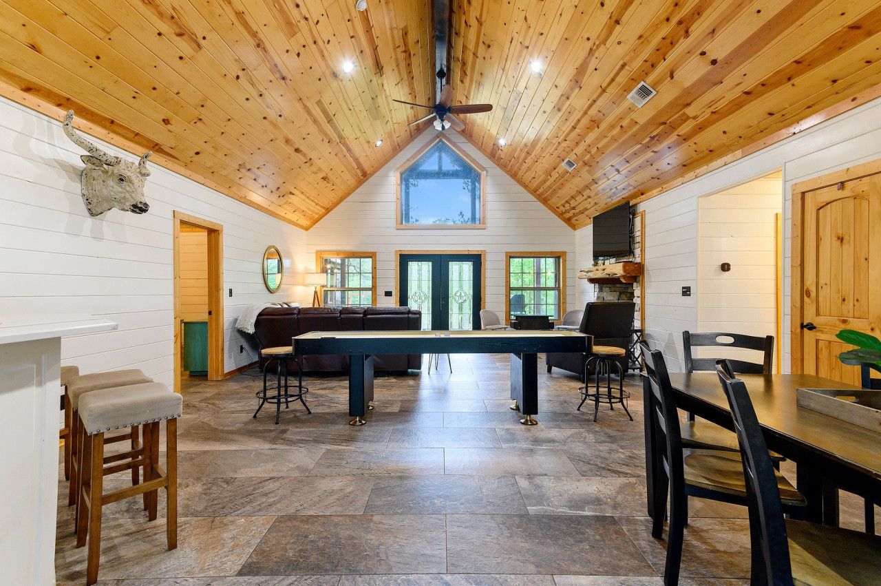 A spacious room with a high ceiling, a central table, and seating arrangements.