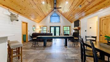 A spacious room with a high ceiling, a central table, and seating arrangements.