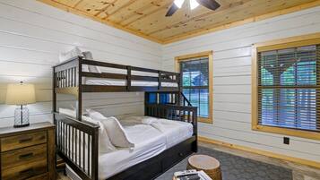 A bunk bed with a wooden headboard, a bedside table with a lamp, and a window with blinds.